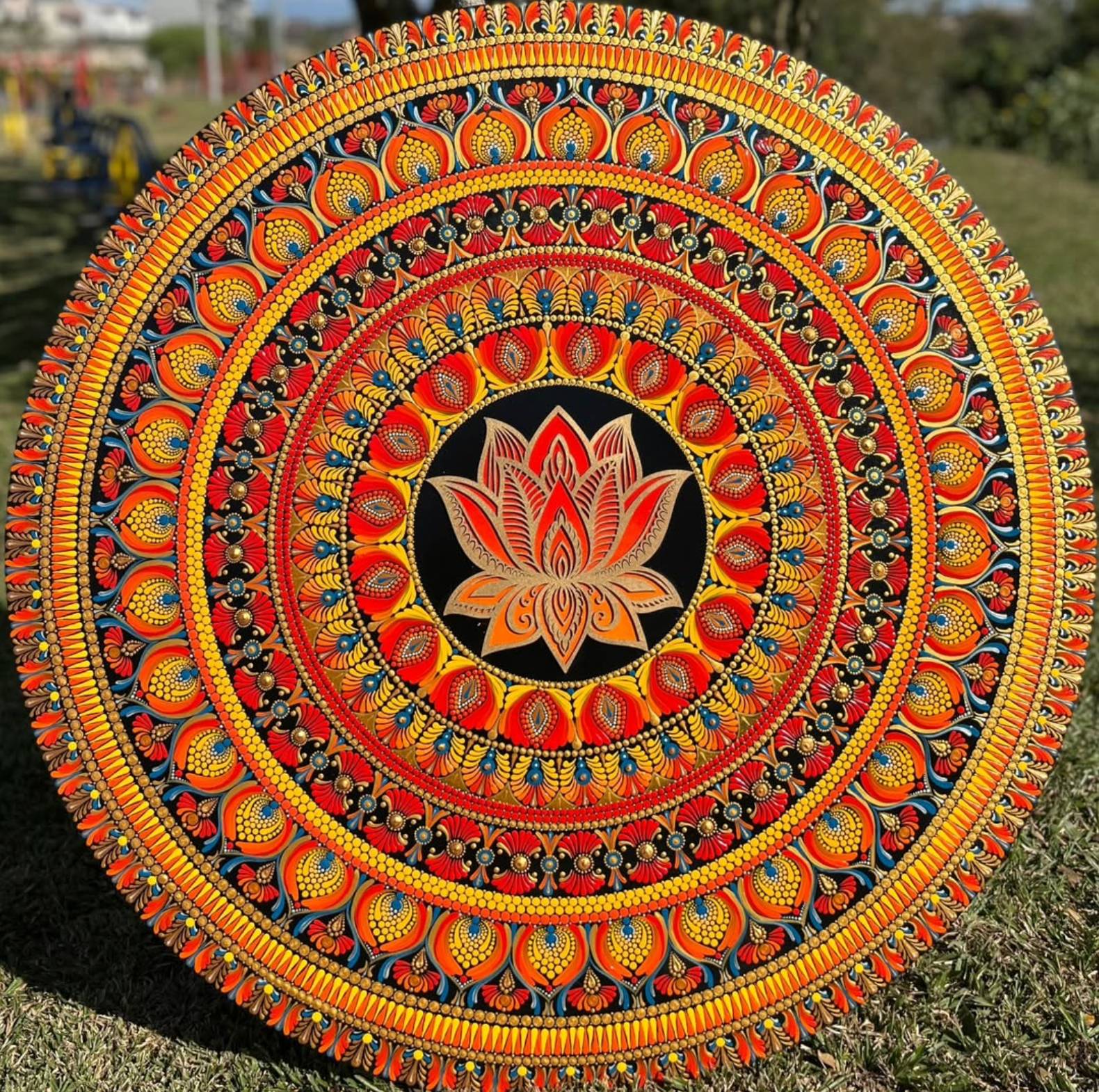 Mandala grande em uma parede de sala de estar, com tons quentes de laranja e amarelo.